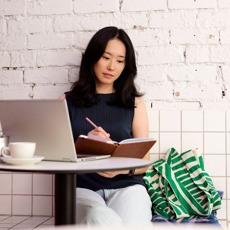 Student at a table with a laptop and book