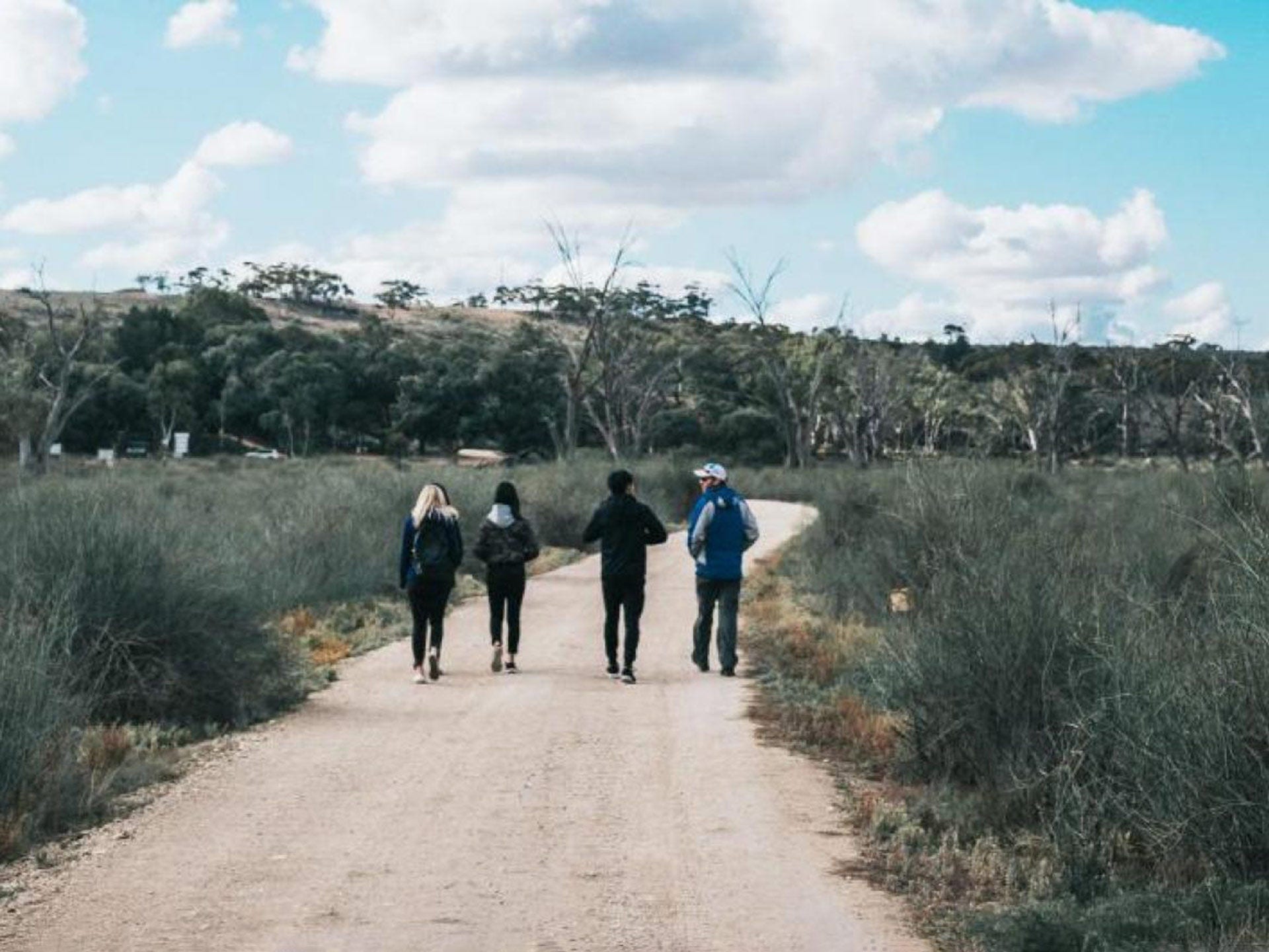 Students walking on a dirt path in a rural location