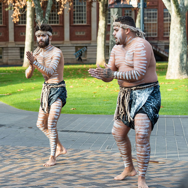 Two First Nations people performing a Welcome to Country in the university courtyard