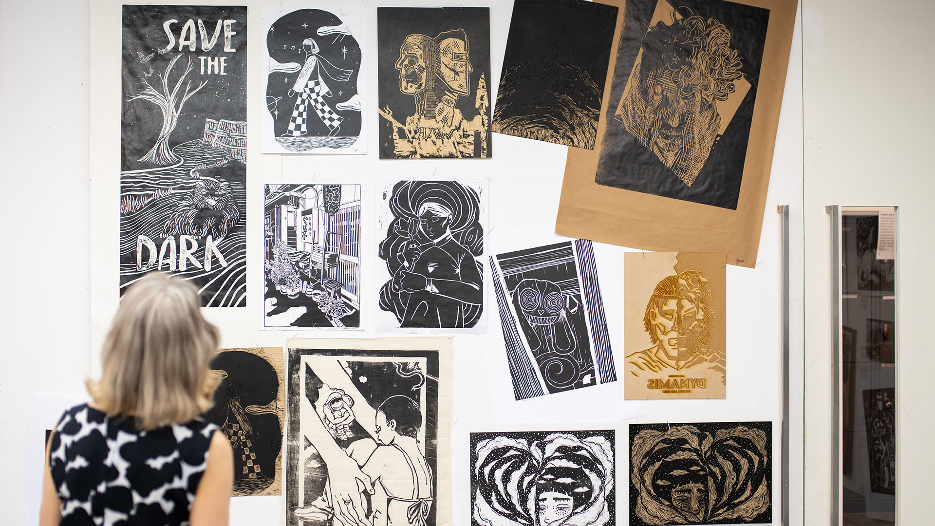 A person looking at a gallery wall of various art pieces