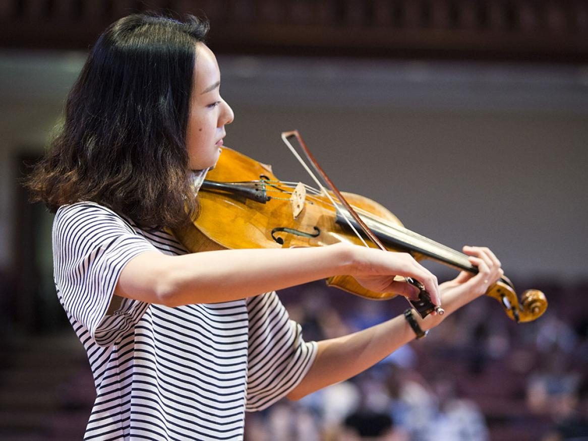 Music student playing the violin in front of an audience